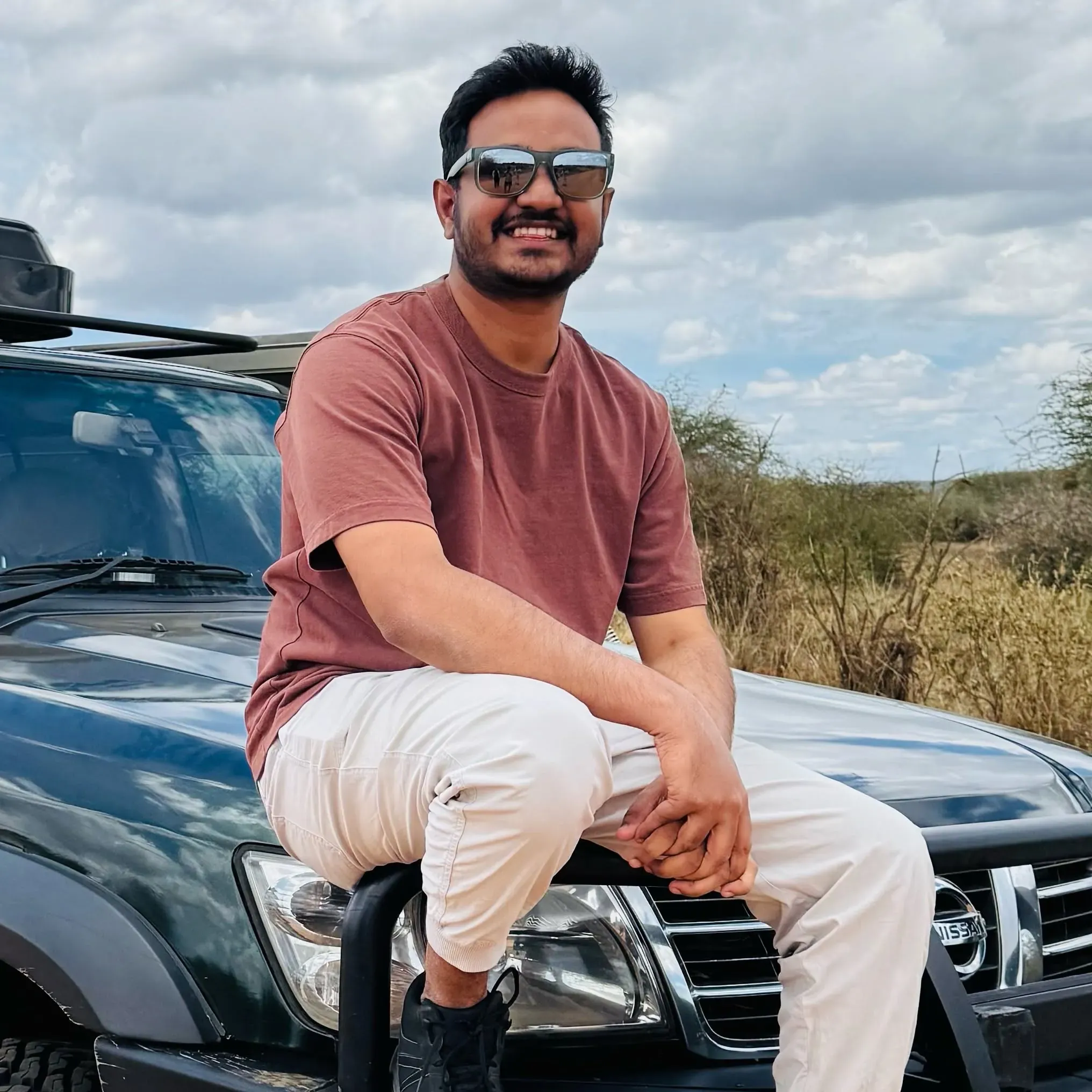 Udara Karunarathna sitting on the bonnet of a safari jeep